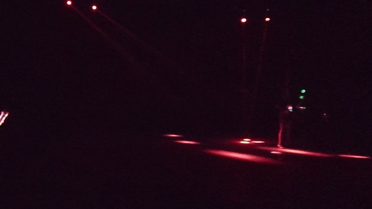 At 0:02, the performer is positioned toward the right side of the San Jose del Cabo stage with red floor light and small blue and green points nearby.