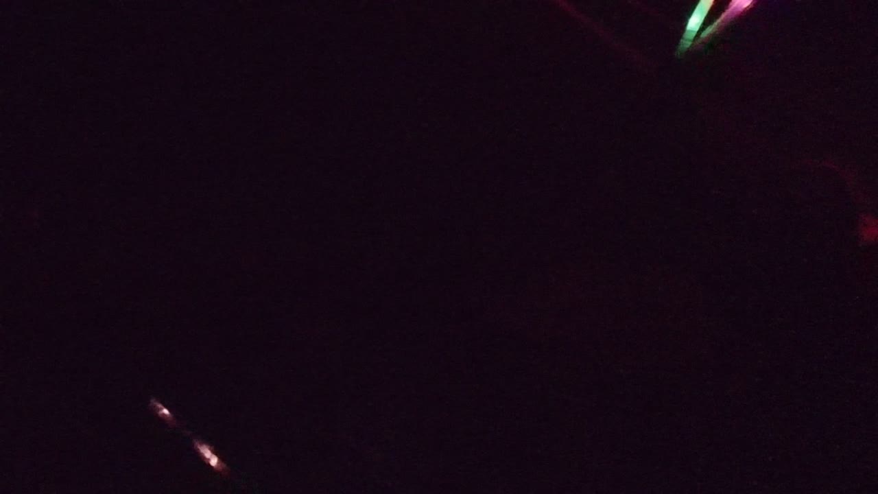 Dark road scene with a bright red streak and scattered small lights.
