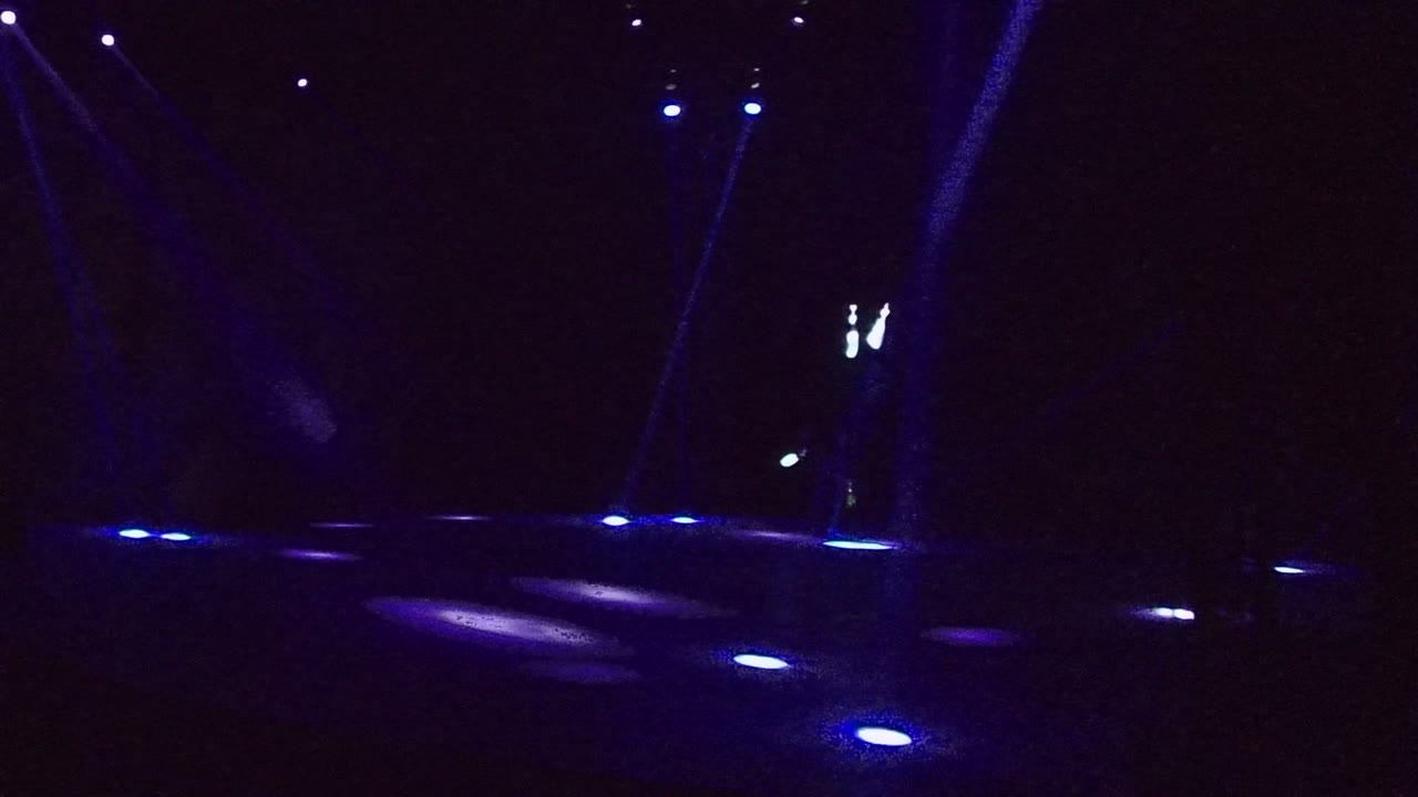 Blue and violet beams crossing a dark outdoor walkway