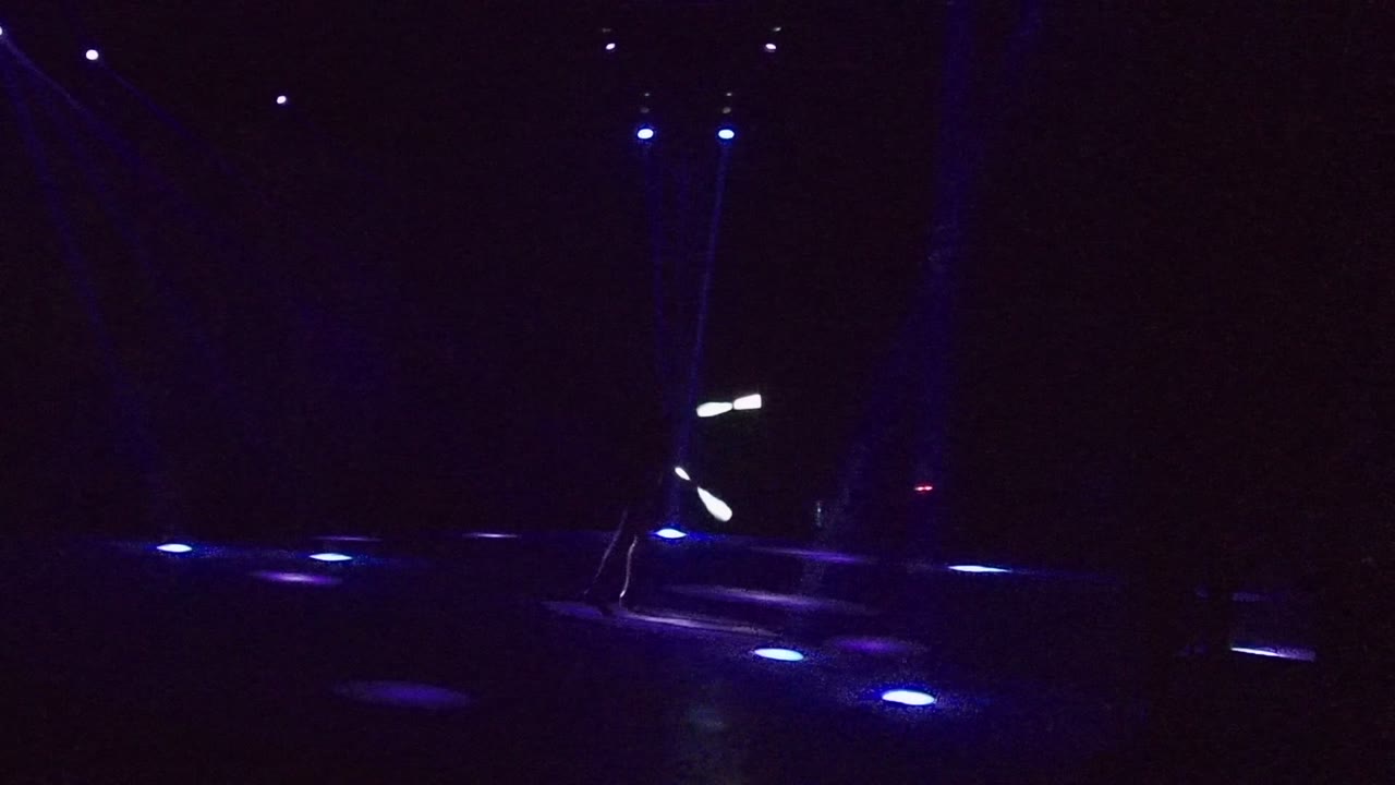 Blue-lit stage with light wand streaks near center and dark background.