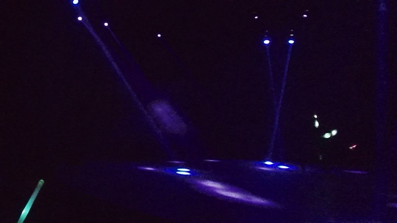 Blue light beams cross a dark road at night.