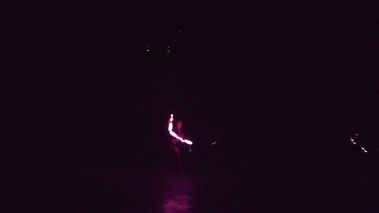 At 0:00 in San Jose Del Cabo, pink glow sticks appear at the left edge over dark water, with faint magenta reflection below and distant points of light across the frame.