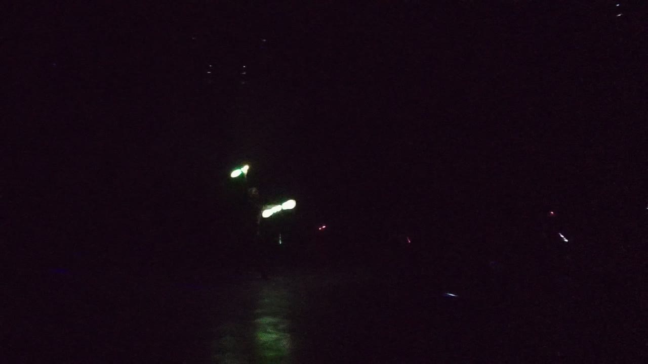 At 0:02 in San Jose Del Cabo, green-white glow sticks appear on the right side above dark water, with a soft green reflection dropping onto the surface.