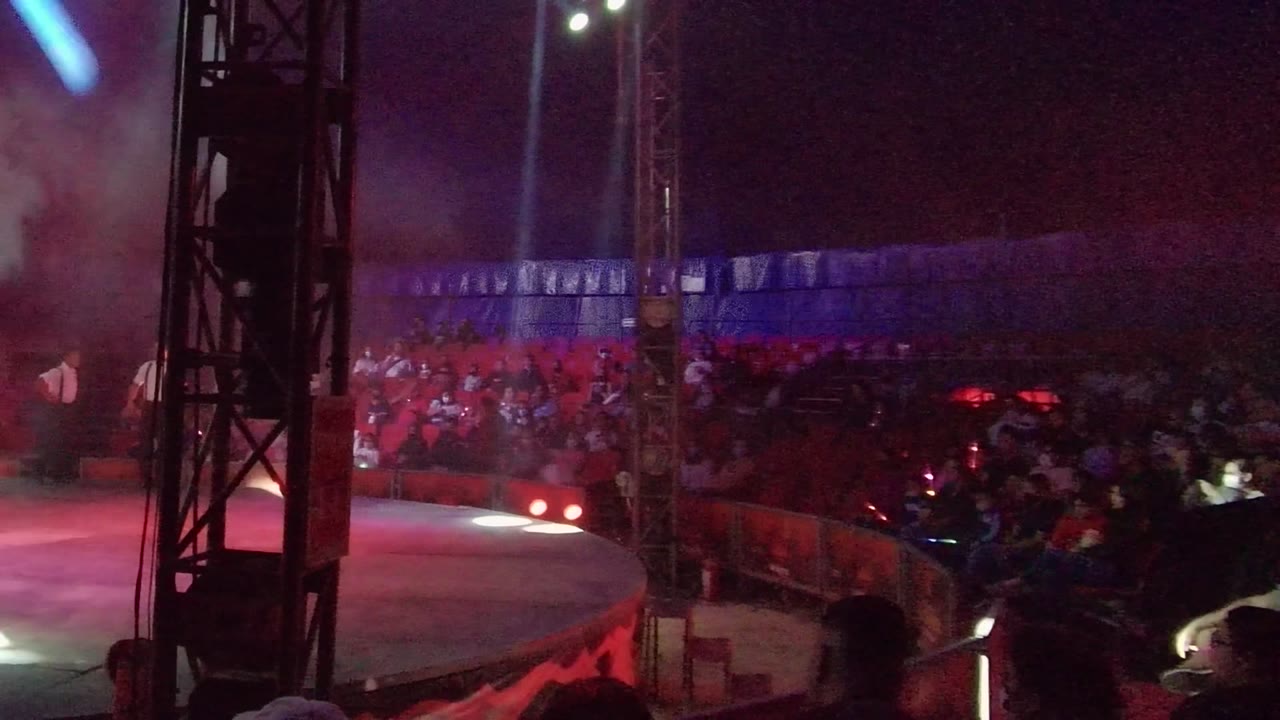 Stage and audience under red and blue lighting with a red chair