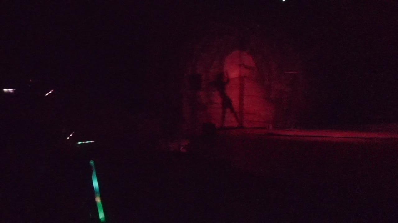 Dark stage in San Jose Del Cabo with the red backdrop more visible and a green accent light rising from the lower foreground.