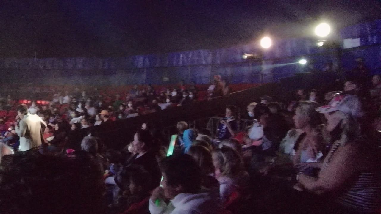 Performer in white near the audience and stage.
