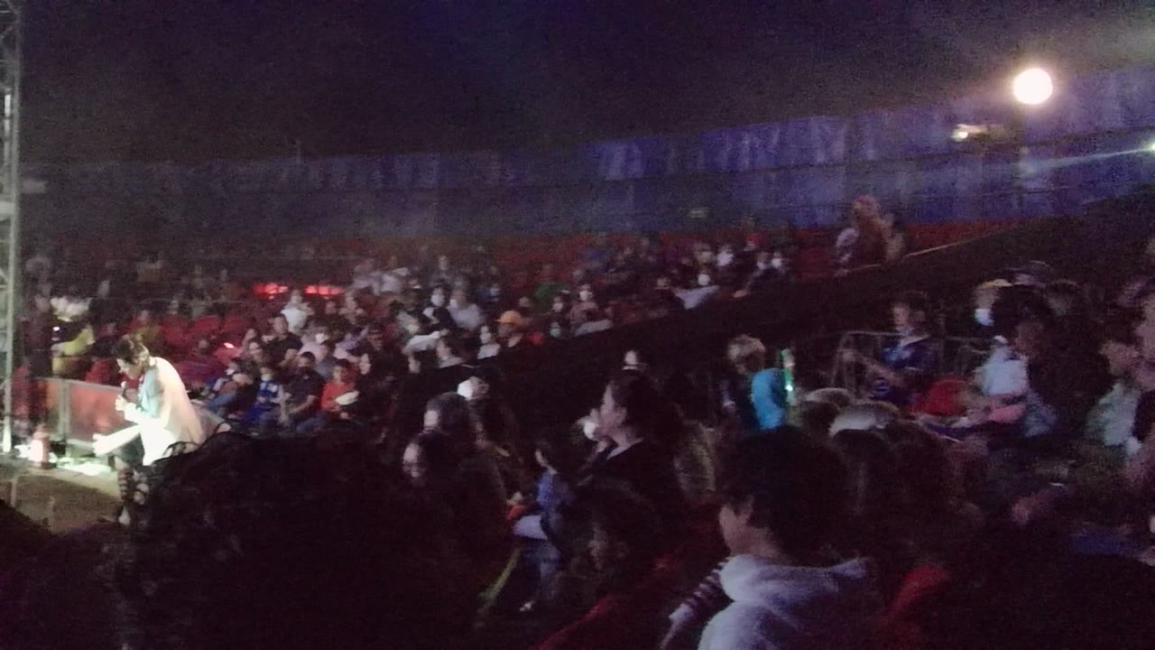 Spectators fill the red seating while a bright pool of stage light and metal support tower frame the right side of the San Jose Del Cabo venue.