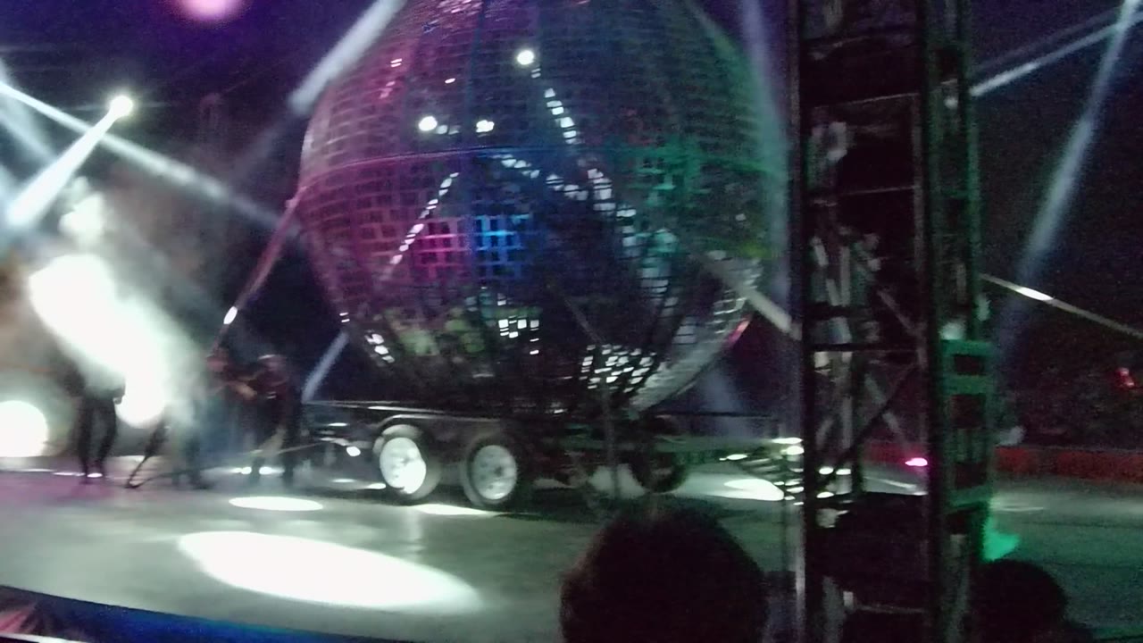 In San Jose del Cabo, the reflective sphere sits to the right of a vertical truss as a performer moves near the bright smoke-filled light source on the left.