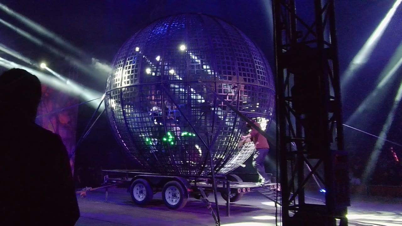 Silhouetted person in front of a reflective stage sphere.
