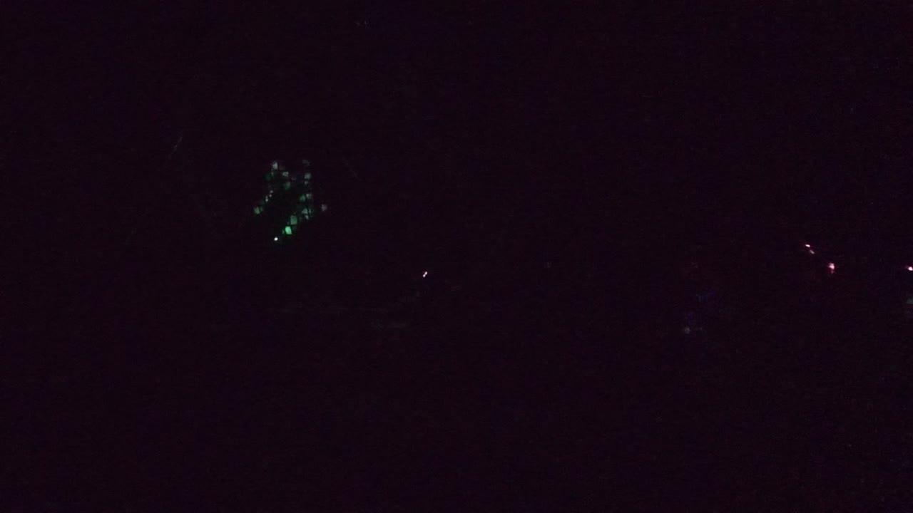 Large dim mesh-like form with green lights near the lower left.