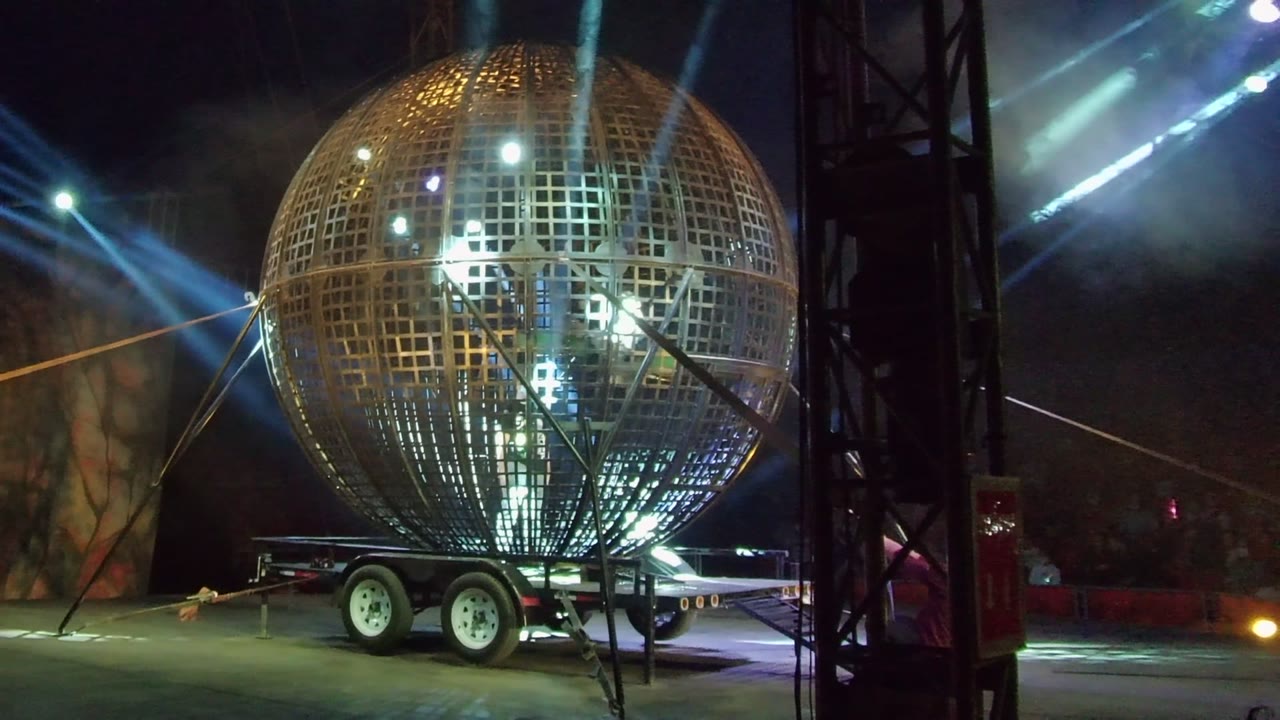 Golden grid sphere remains centered in San Jose Del Cabo, Baja California Sur, with internal highlights, blue light beams, trailer wheels, and no visible people.