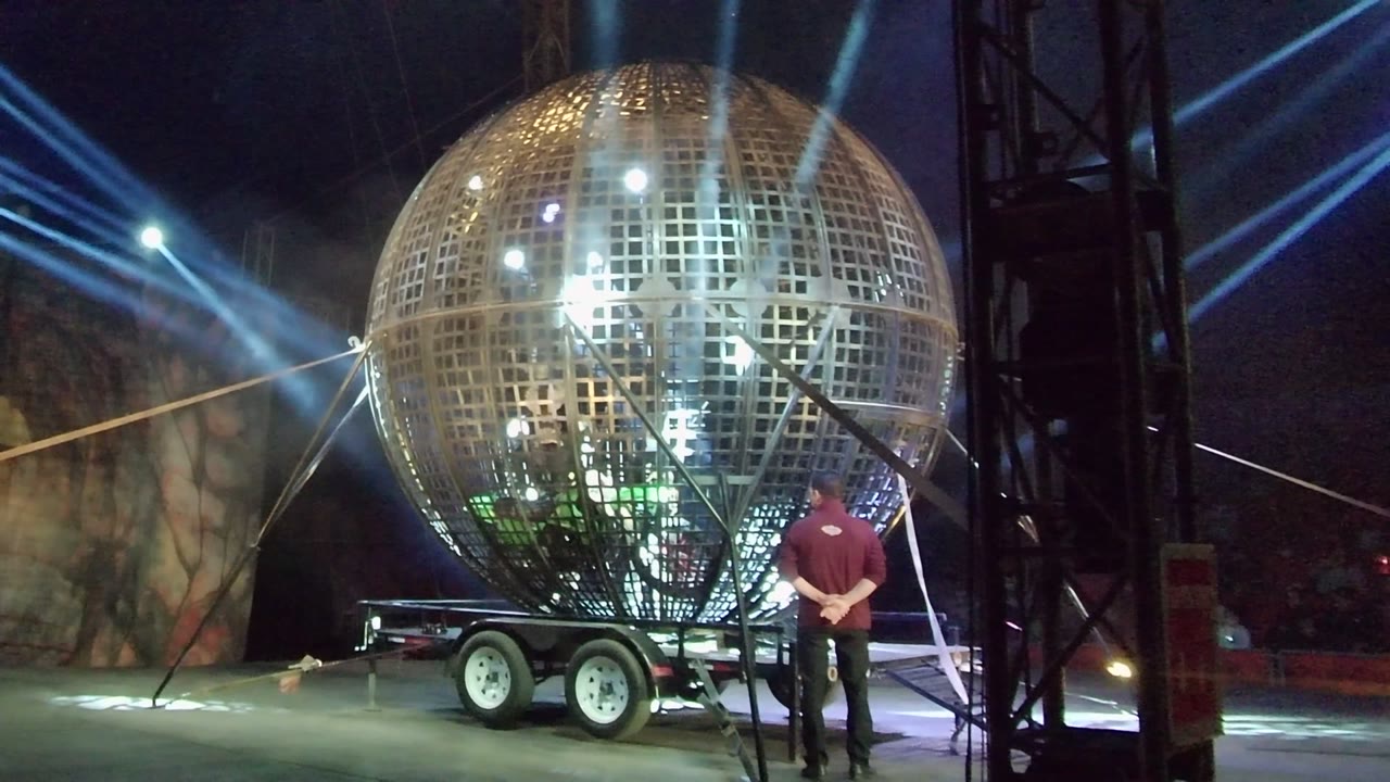 A reflective golden sphere on a trailer fills the center of the San Jose del Cabo stage scene, with a person in red standing near the right support area.