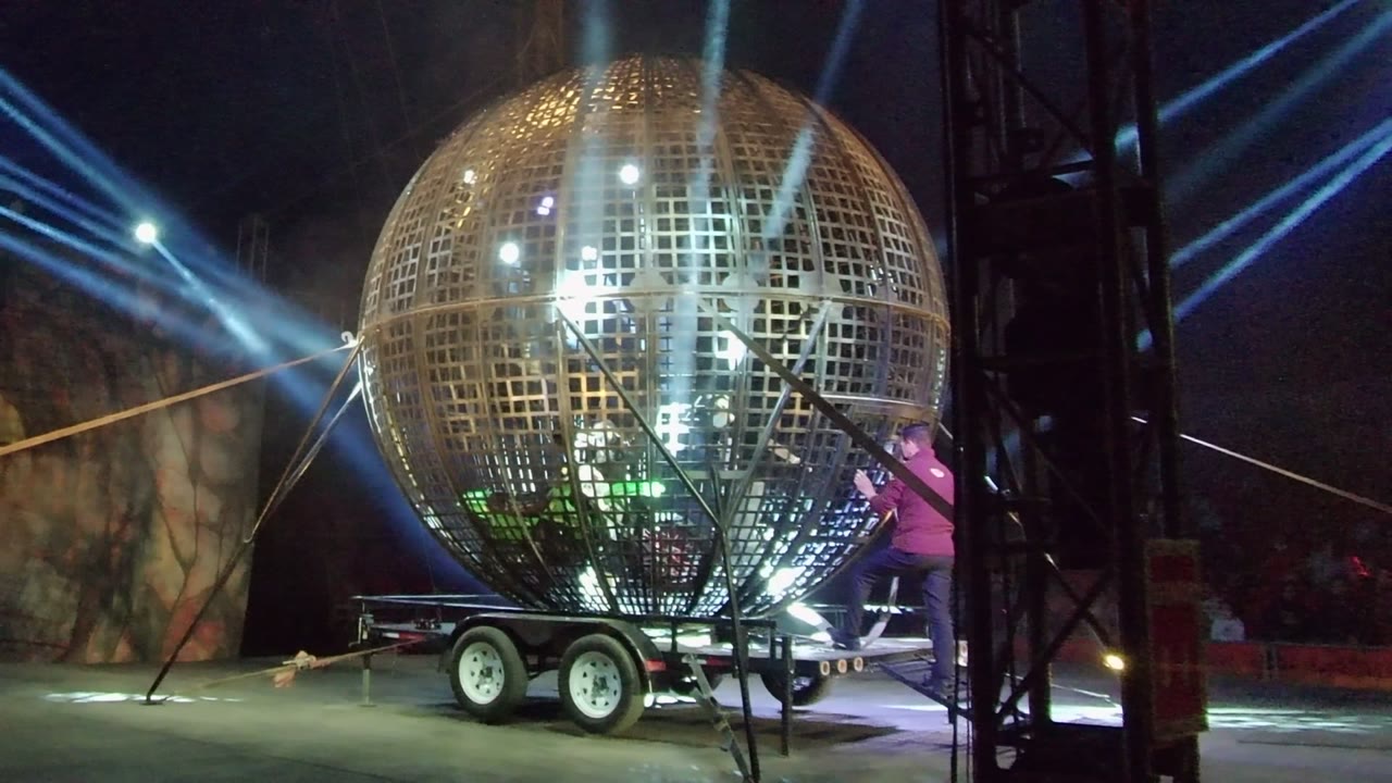 Golden stage sphere on trailer with blue beams and stage rigging.