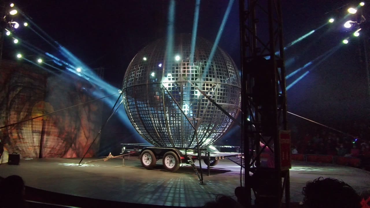 Stage globe and trailer with blue beams and a person near the left edge.