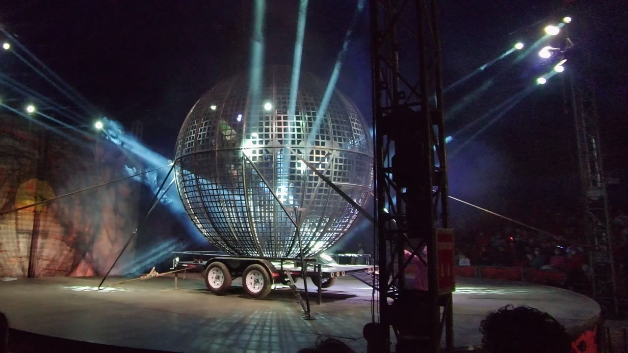 Mirrored sphere on a trailer with spotlights crossing through smoky stage air.