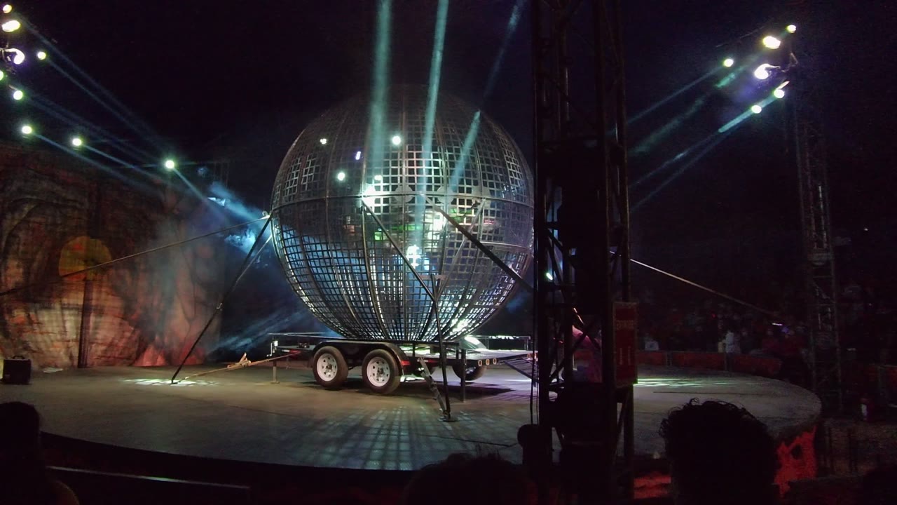 The spherical stage prop remains centered in San Jose Del Cabo, Mexico, as blue beams pass through haze near the painted backdrop and no recognizable people are visible.