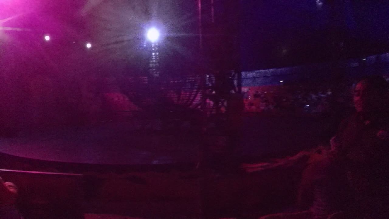 Circular stage area with pink and blue lights above rows of seats.