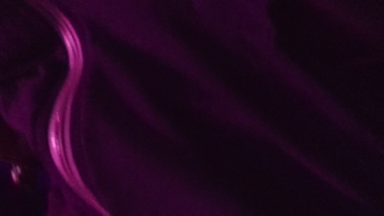 Close-up in a dark San Jose del Cabo venue with a curved glowing pink strip or seat edge filling the left side and no clearly visible faces.