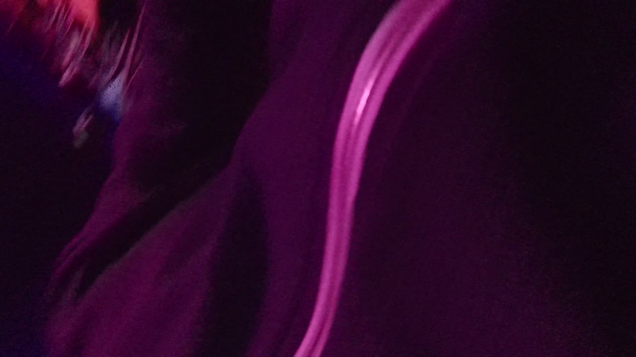 Dark audience area with purple lighting and indistinct seated figures