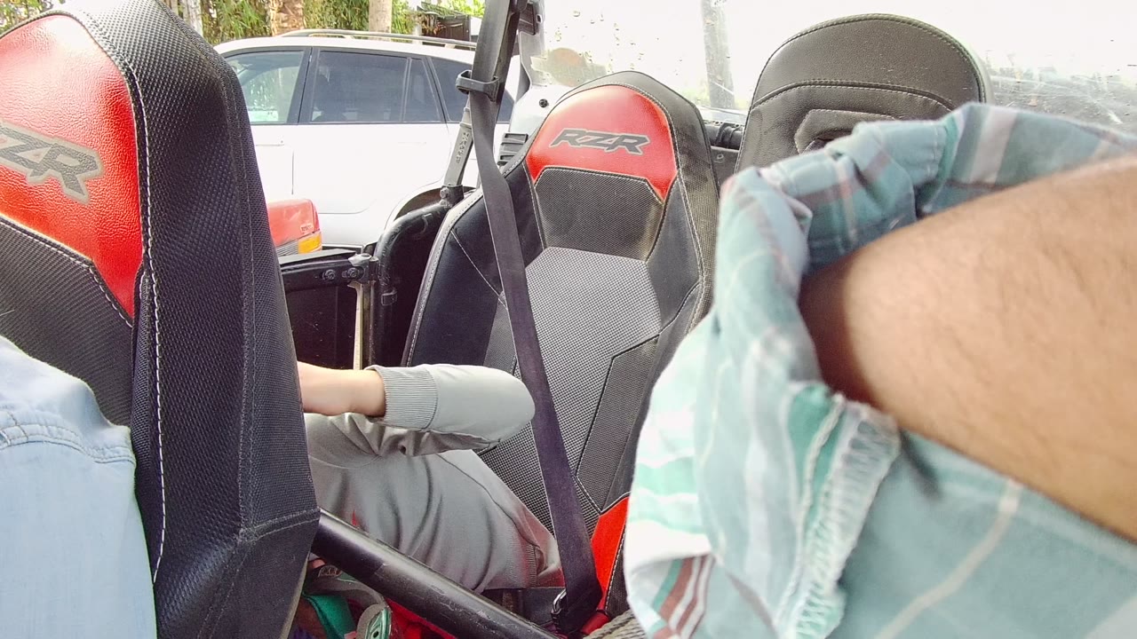 Close view of off-road vehicle seats with a passenger partly hidden behind them.
