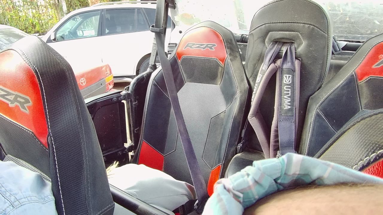 The Los Cabos clip shows the RZR seat backs and harnesses while a blue shirt or sleeve appears low in frame, suggesting a passenger moving into place.