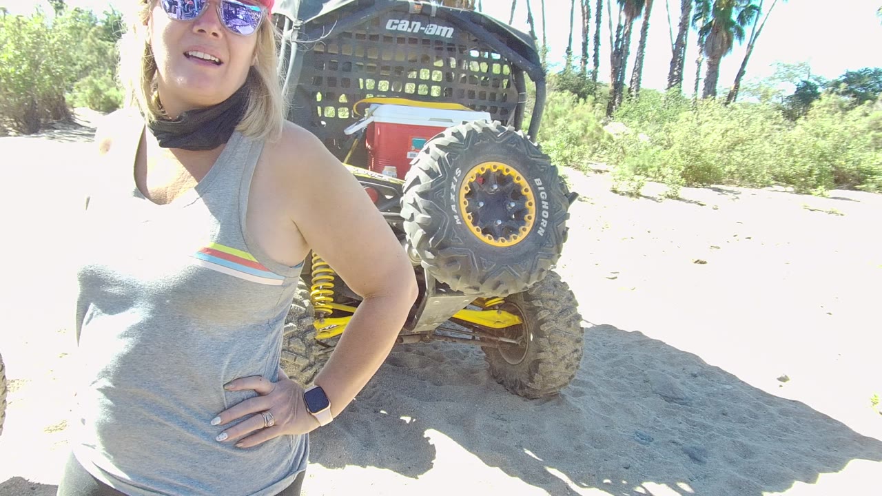 Woman stands with hand on hip near a Can-Am off-road vehicle tire.