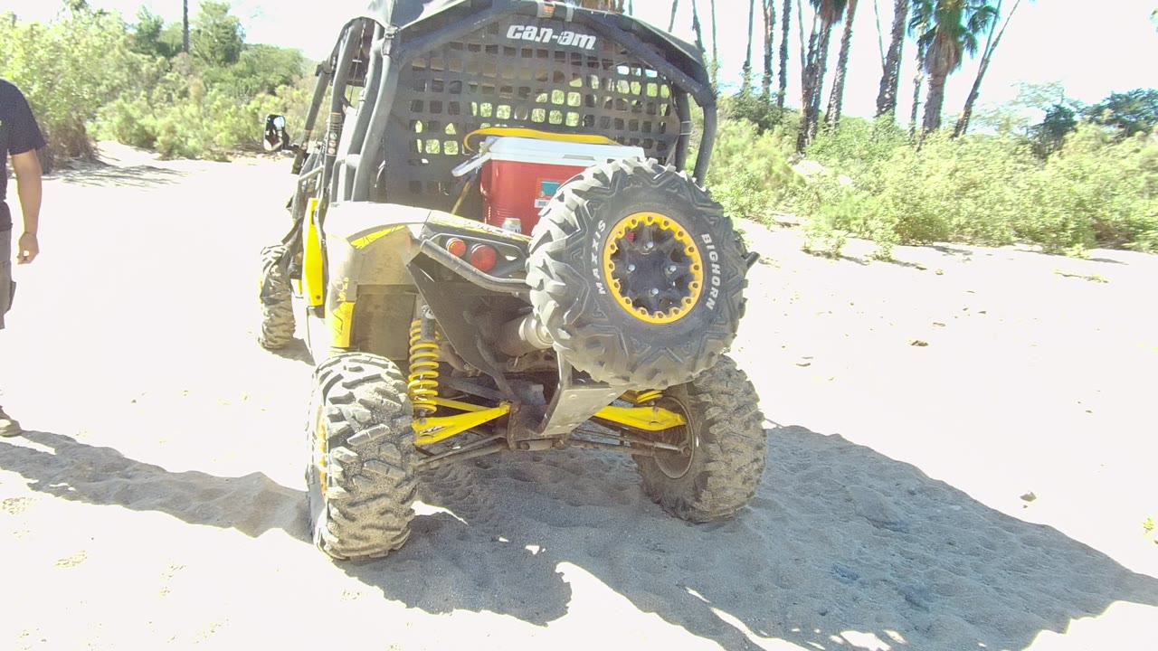 Off-road vehicle parked on sandy ground with a person partly visible on the right edge.