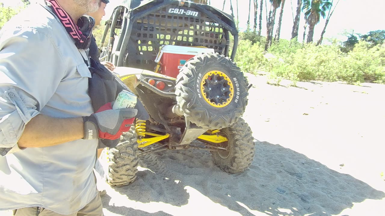 Cropped man in gray jacket standing beside an ATV spare tire.