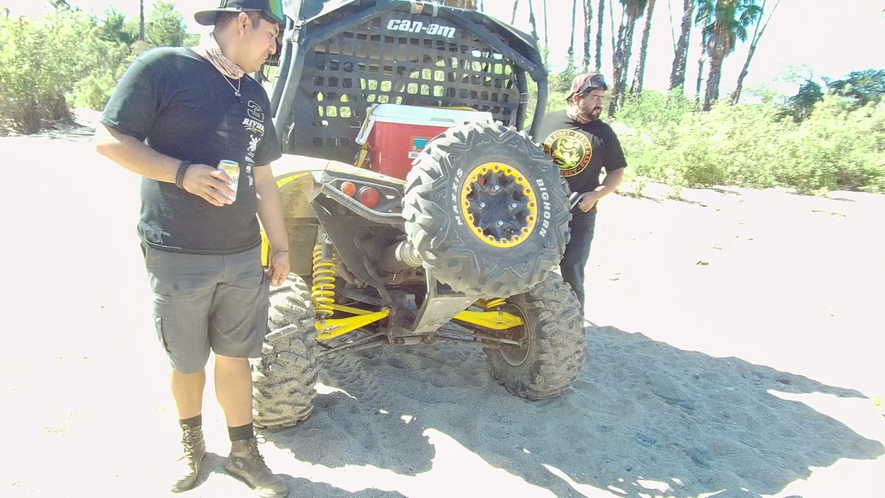 Man holding a cup near an off-road vehicle as another man stands behind it.