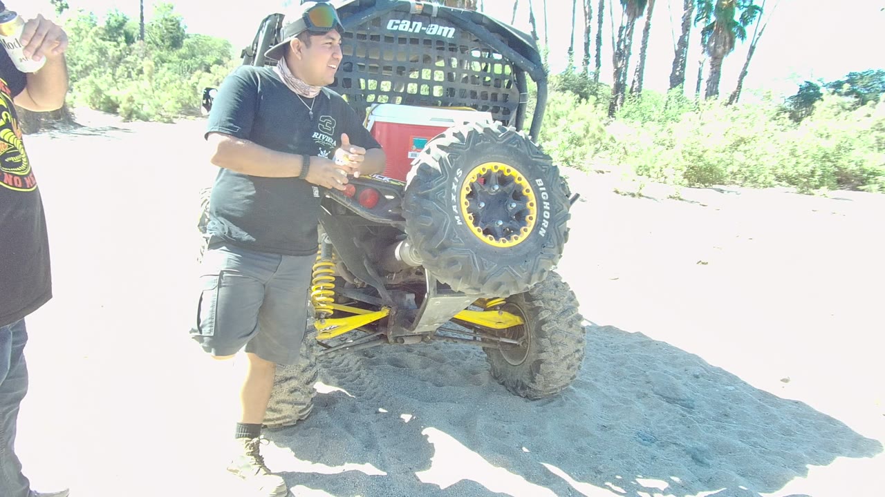 Man standing beside a Can-Am off-road vehicle in bright sun.
