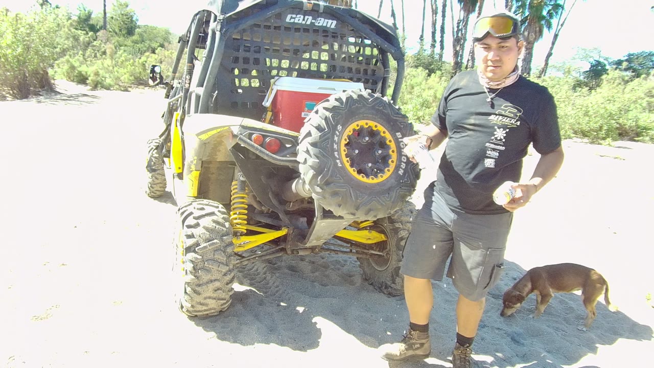 Man stands beside the off-road vehicle holding a can while a dog stays near the tire.