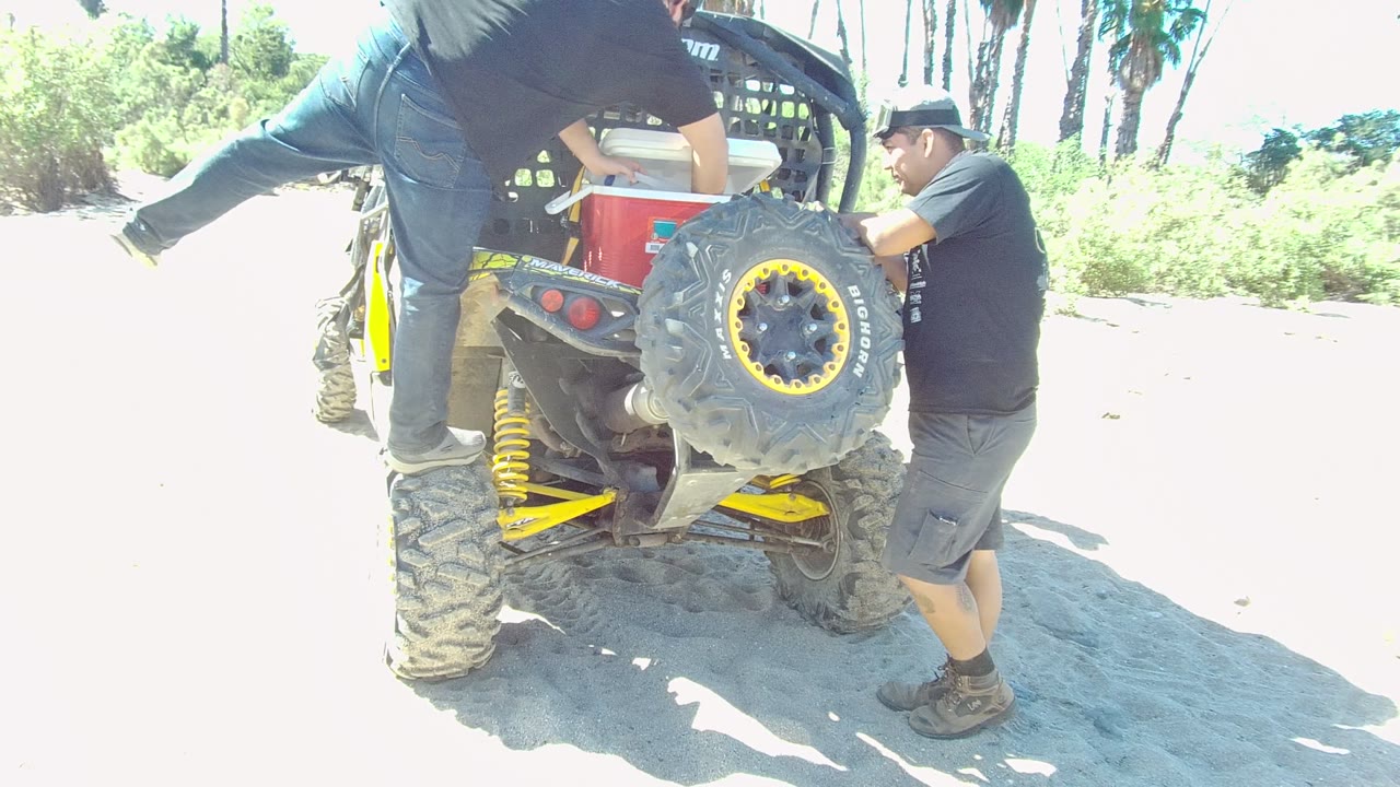 At 0:02 in Los Cabos, the man on the ATV is still stepping down while the other man stays at the rear corner near the wheel and cargo rack.