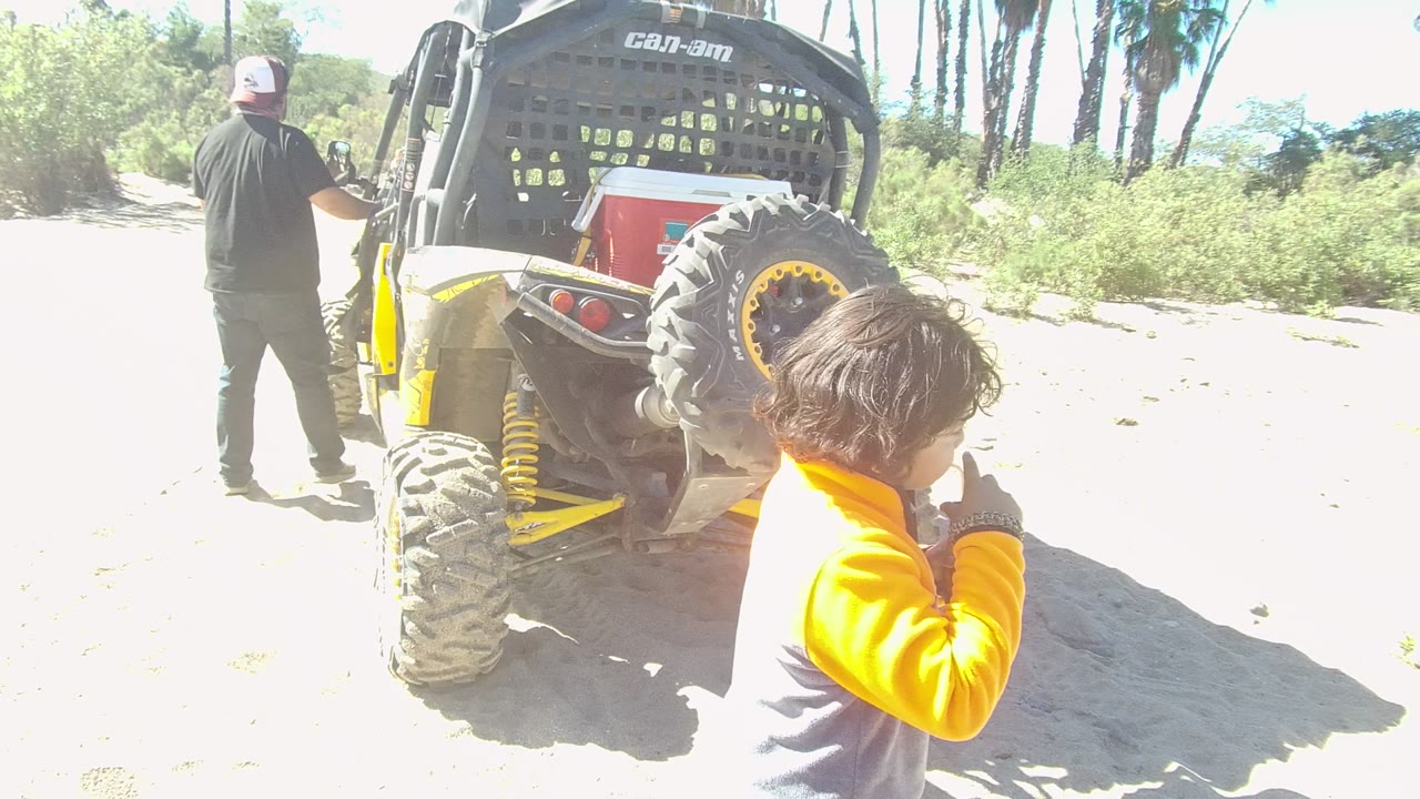 Man and child beside a yellow and black off-road vehicle.