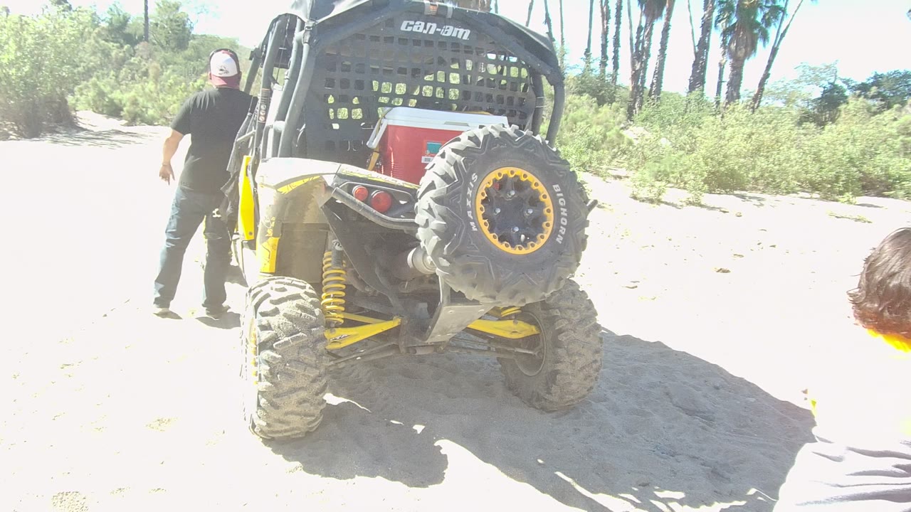In Los Cabos, Baja California Sur, the child is partly cropped at the right edge while the man remains near the rear of the off-road vehicle against palm trees and brush.