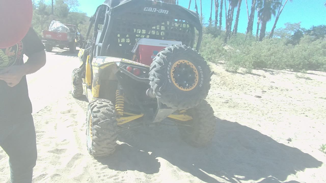 In Los Cabos, Baja California Sur, the red disc and a person's torso fill more of the foreground while the parked off-road vehicle remains visible behind them.