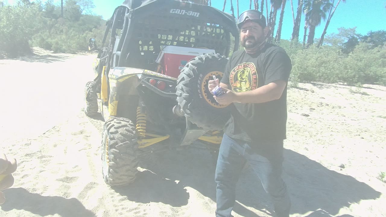 Man holding a bottle beside the rear of a dune buggy.
