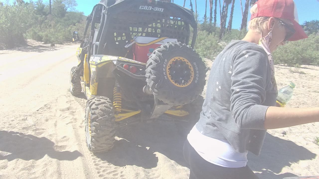 Person in red cap walking past a parked dune buggy.