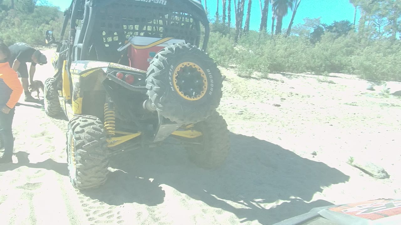 Person bending near off-road vehicle on sand