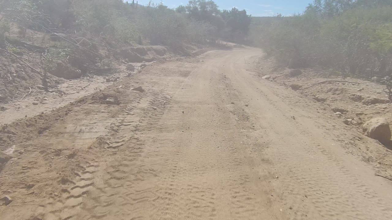 Dusty road passing eroded roadside banks