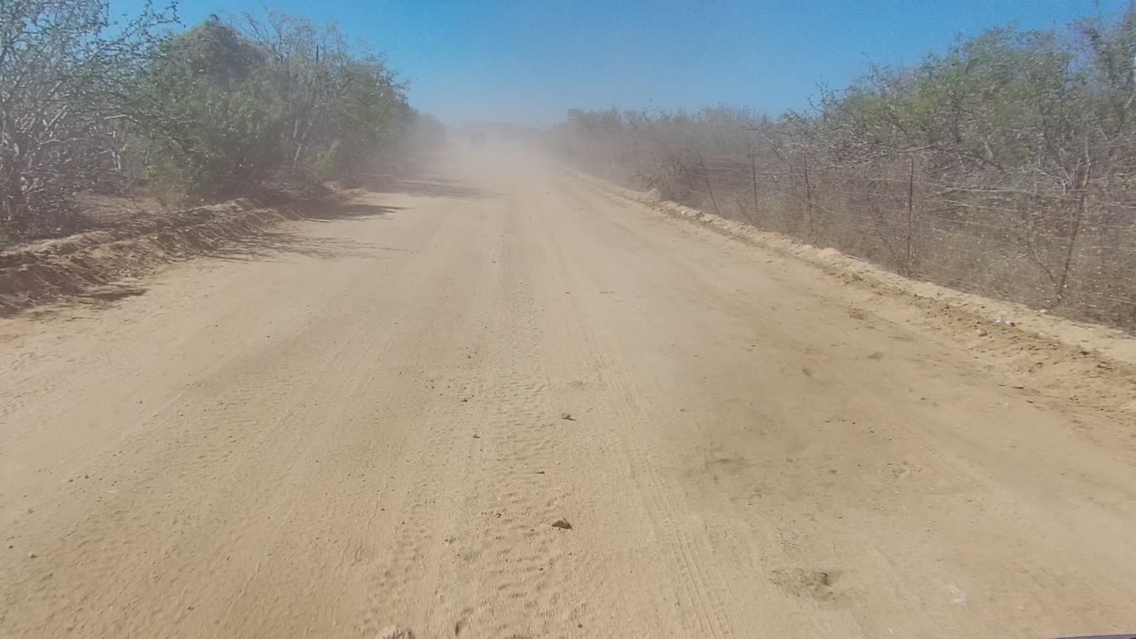 Dirt road disappearing into a light dust cloud