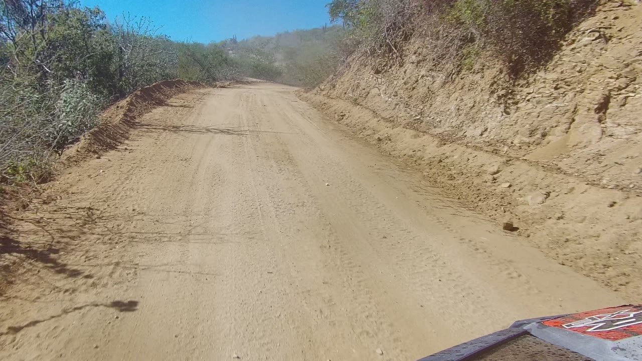 Vehicle edge at bottom of winding dirt road scene