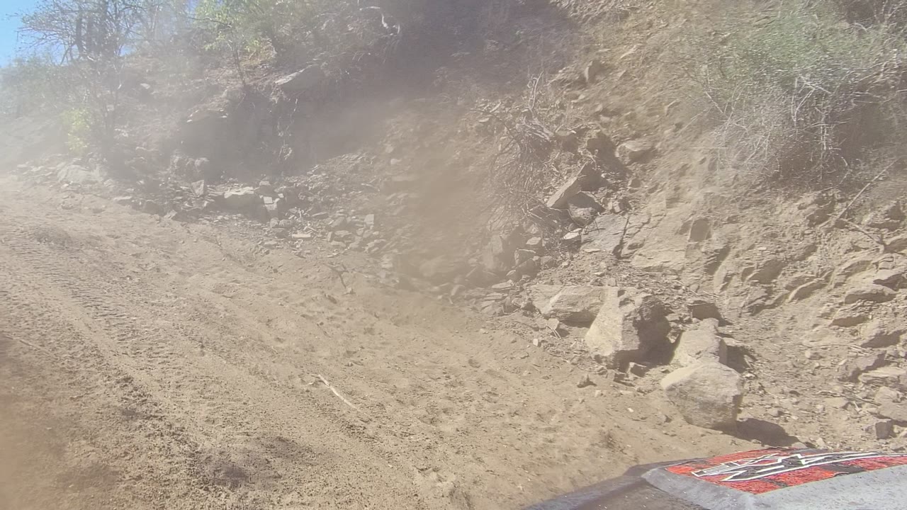 Rocky dirt track curving between scrub-covered slopes.
