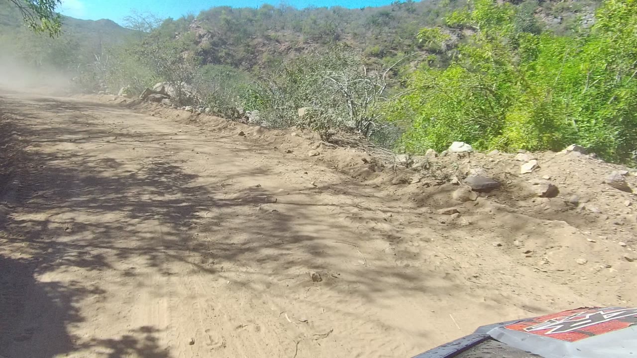 Sandy road with rocks and brush beside a dusty track