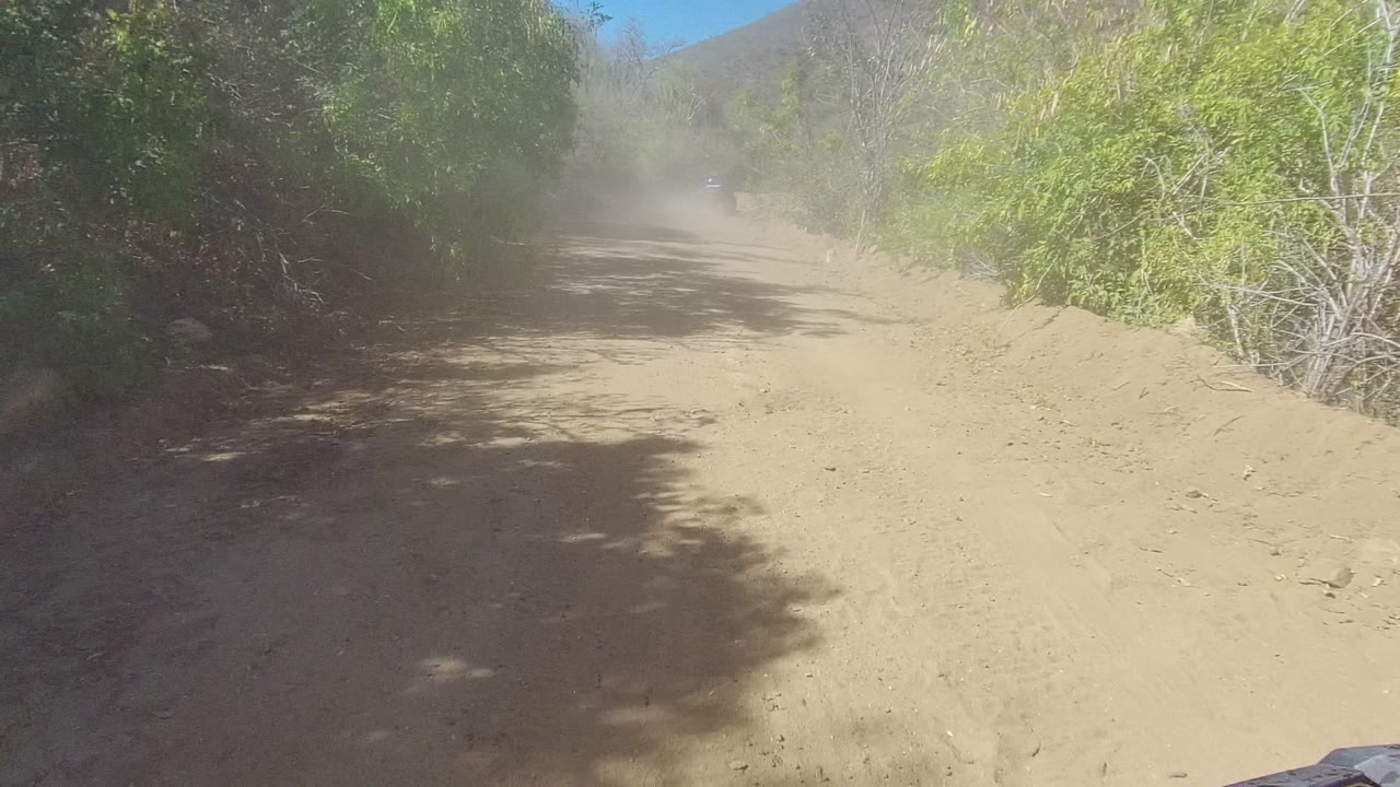 Winding dirt road with dust hanging above the path