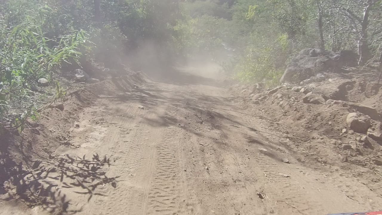 Large roadside boulder beside a dusty dirt track