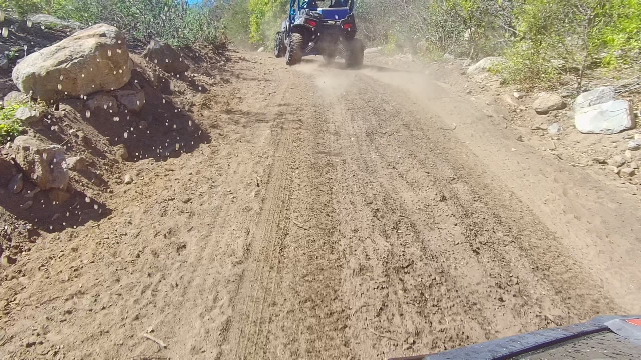 Off-road vehicle on muddy track beside boulders