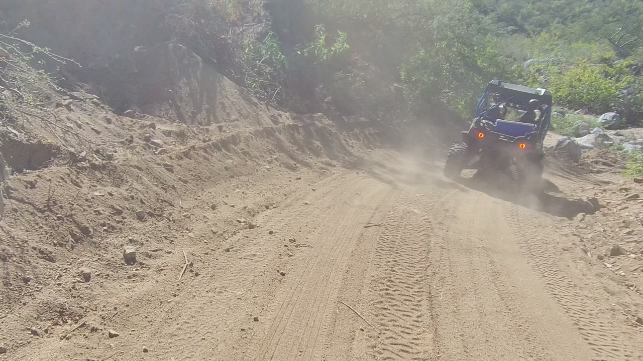 Off-road buggy farther up a dusty trail beside rocky embankments