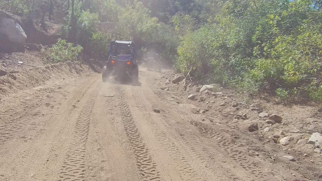 Off-road jeep farther up a rutted sandy trail with dust behind it