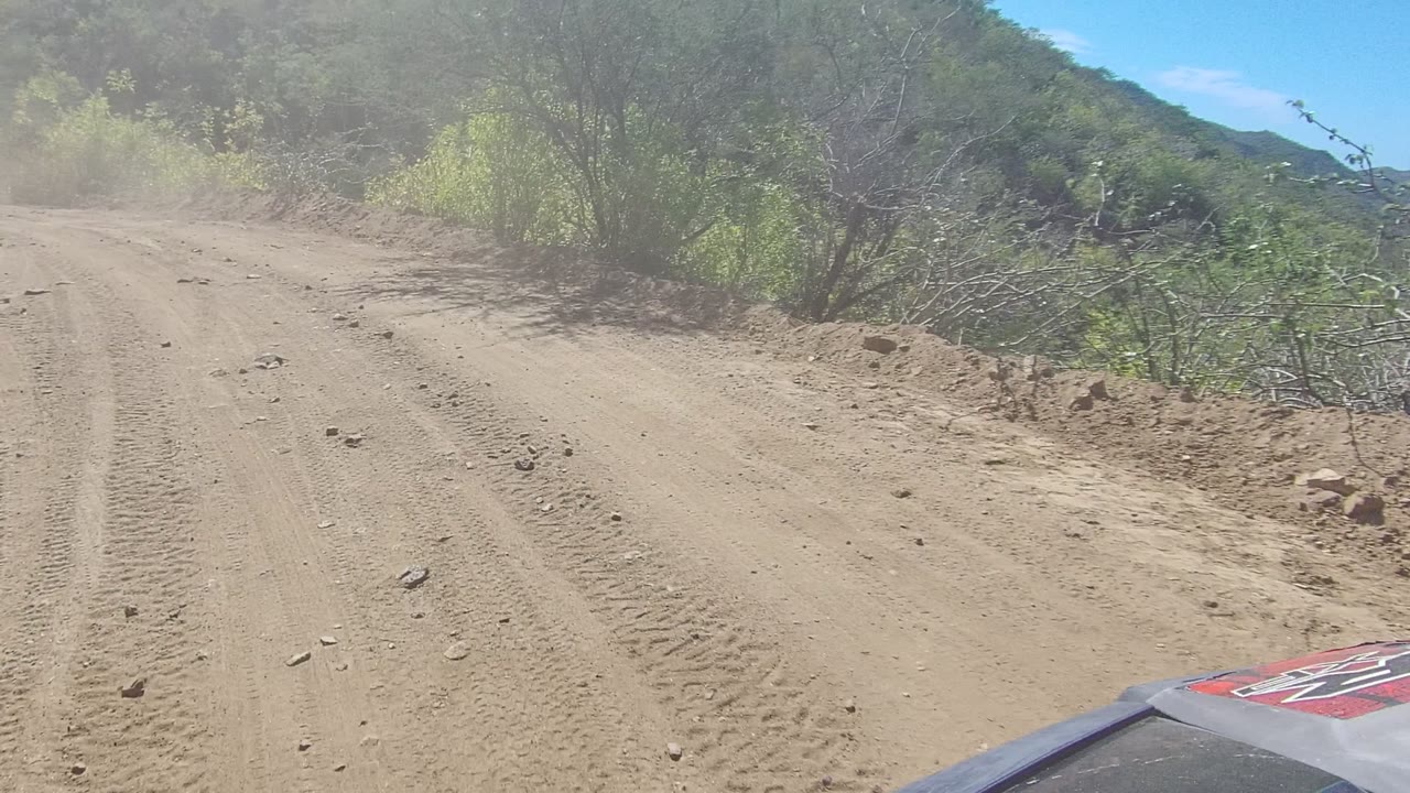 Unpaved road climbing between scrub and hills