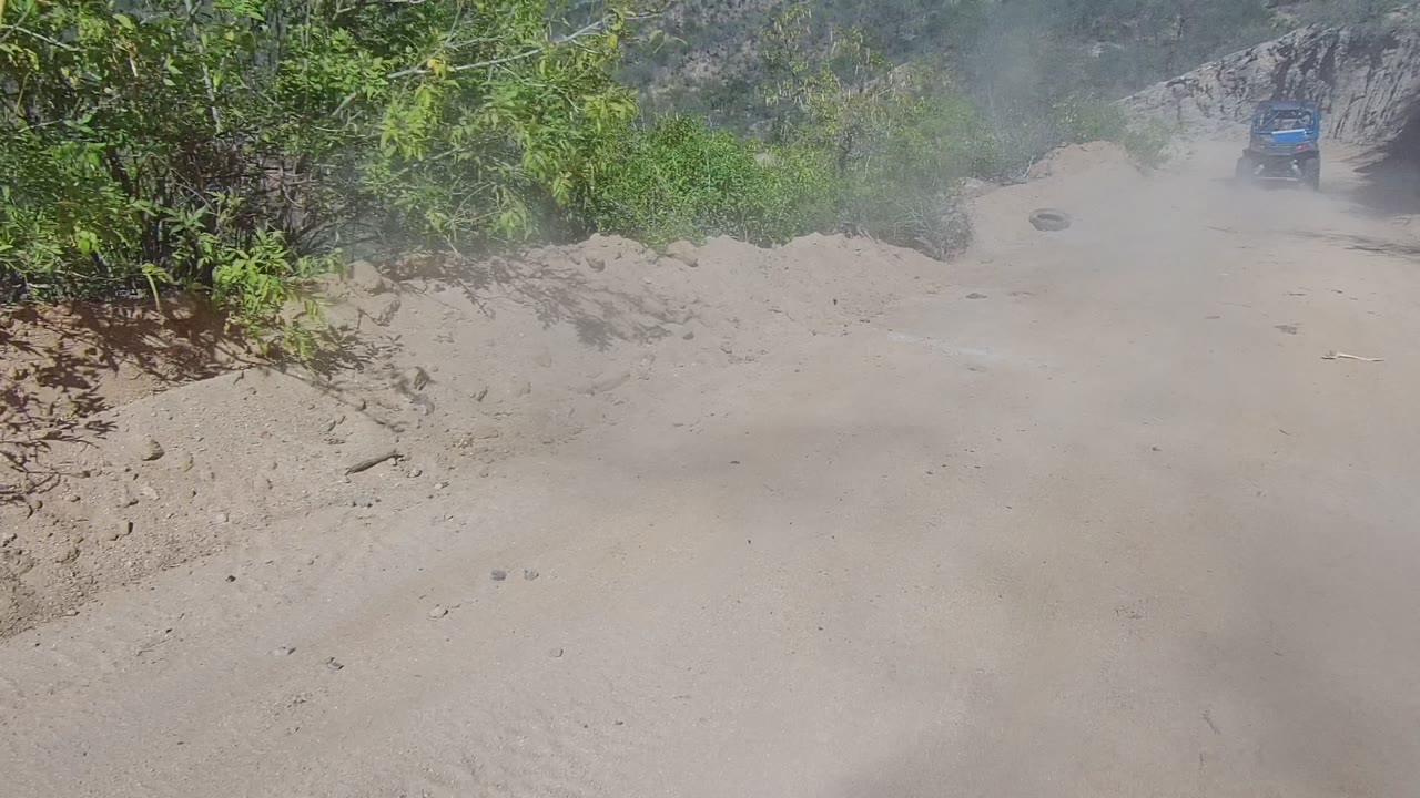 Blue truck in the distance on a dusty dirt road.